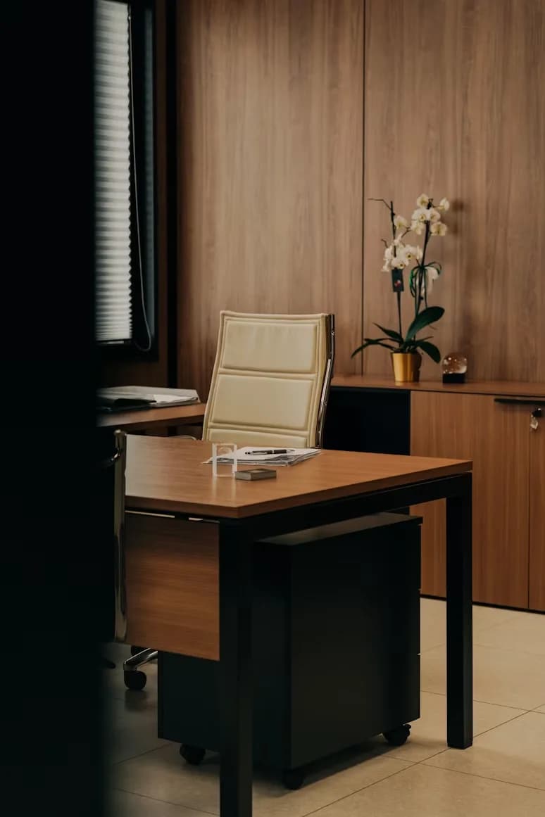 A wood-panelled office with a single desk, a leather chair and an orchid on the cabinet